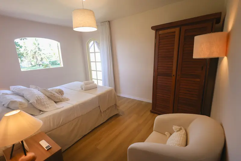 Suíte 1, com cama queen, poltrona e armário de madeira